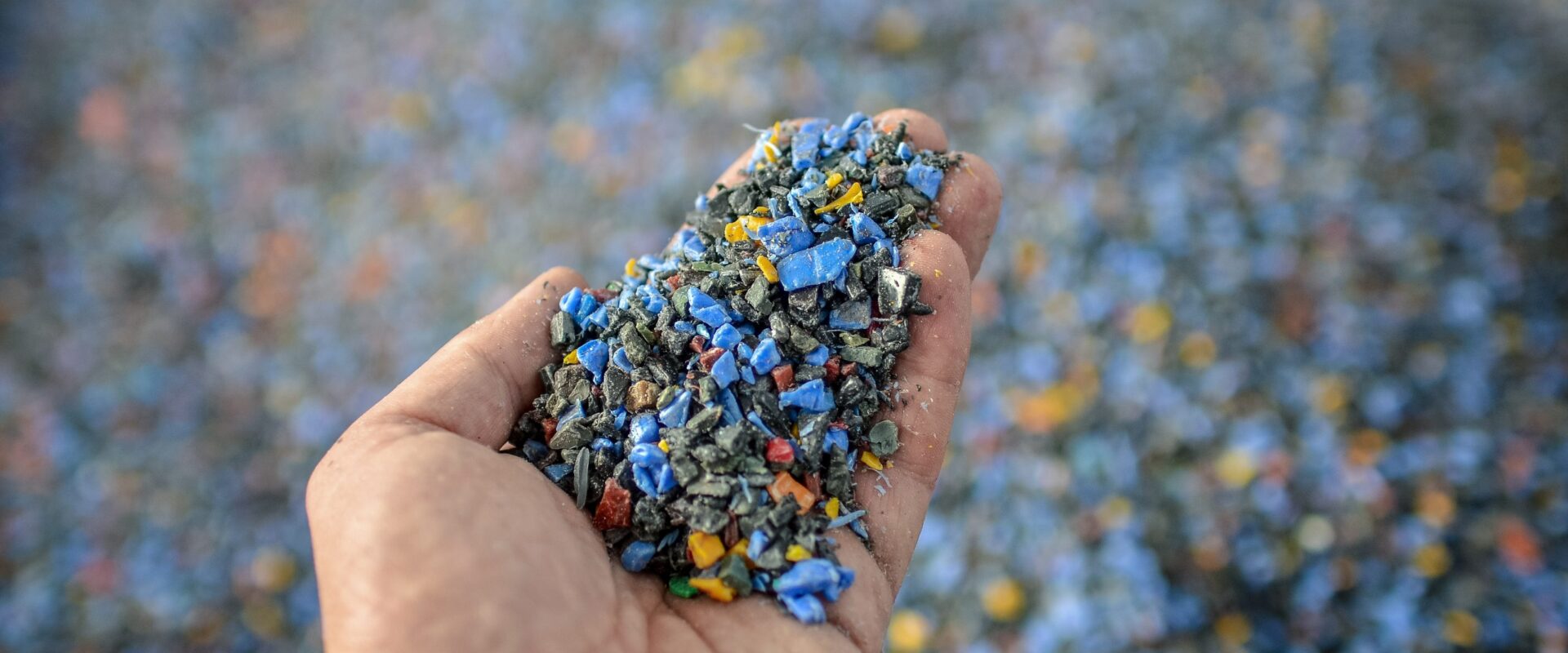 Hand holding recycled plastic chips as raw material in production.